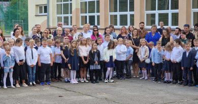 Uczniowie stoją obok siebie, a za nimi ich rodzice.