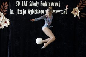Uczennica trenująca akrobatykę taneczną podczas występu z piłką na scenie