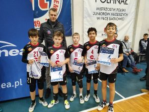 Na zdjęciu znajduje się pięciu zawodników klubu UKS Czerwonak ustawieni w rządzie, trzymający dyplomy oraz nagrodę za najlepszego gracza zespołu. Za nimi jest były zawodnik I ligowego zespołu z Bydgoszczy Maciej Jurkiewicz. W tle znajdują się banery reklamowe firmy ENEA oraz Mistrzostwa Polski Juniorów Młodszych w Piłce siatkowej.