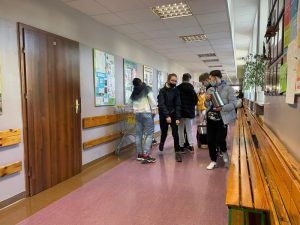  Uczniowie podczas przerwy na szkolnym korytarzu prezentują nosidła na książki i przybory szkolne w ramach akcji "Dzień bez plecaka"