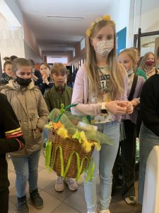 Uczniowie podczas przerwy na szkolnym korytarzu prezentują nosidła na książki i przybory szkolne w ramach akcji "Dzień bez plecaka"