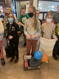 Uczniowie podczas przerwy na szkolnym korytarzu prezentują nosidła na książki i przybory szkolne w ramach akcji "Dzień bez plecaka"