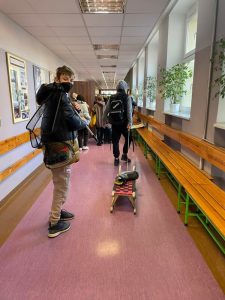 Uczniowie podczas przerwy na szkolnym korytarzu prezentują nosidła na książki i przybory szkolne w ramach akcji "Dzień bez plecaka"