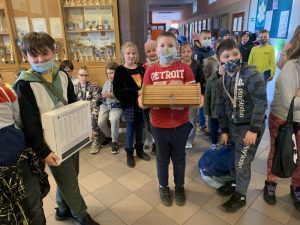 Uczniowie podczas przerwy na szkolnym korytarzu prezentują nosidła na książki i przybory szkolne w ramach akcji "Dzień bez plecaka"