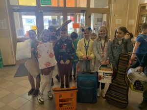 Uczniowie podczas przerwy na szkolnym korytarzu prezentują nosidła na książki i przybory szkolne w ramach akcji "Dzień bez plecaka"