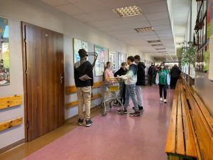  Uczniowie podczas przerwy na szkolnym korytarzu prezentują nosidła na książki i przybory szkolne w ramach akcji "Dzień bez plecaka"