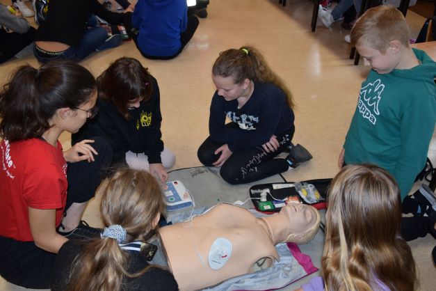 Uczniowie uczą się przeprowadzać pierwszą pomoc - ratowniczka medyczna tłumaczy im co po kolei należy zrobić, uczniowie obsługują AED – defibrylator szkoleniowy