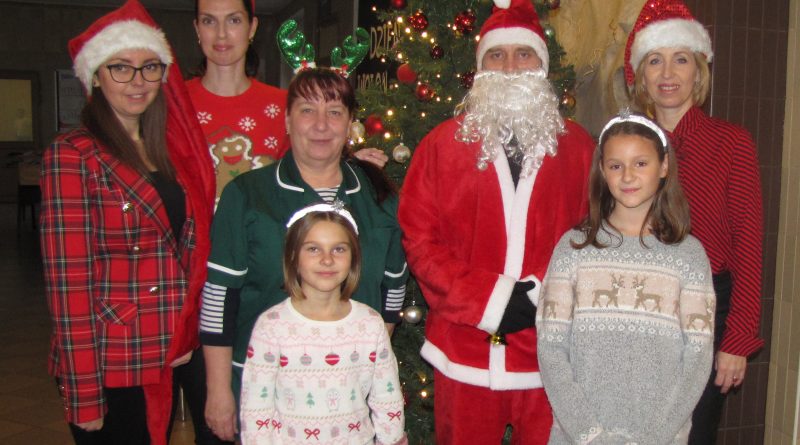 Przedstawiciele Rady Rodziców wraz panią dyrektor i pracownikami szkoły oraz uczennicami. Za nimi przybrana choinka