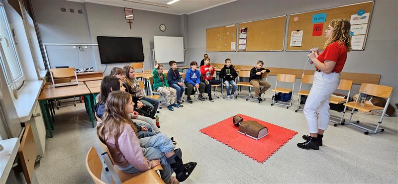 uczniowie obserwują i słuchają pani, która opowiada o pierwszej pomocy