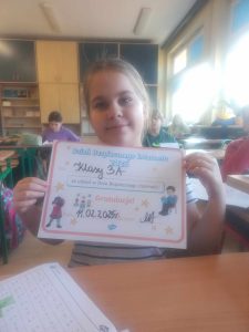 Dziewczynka trzyma w ręach dyplom za udział w Dniu Bezpiecznego Internetu.