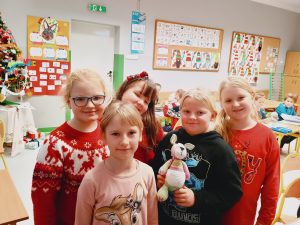 Grupa dziewczynek stoi razem, obok siebie. Jedna z nich trzyma w ręce maskotkę.