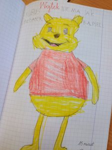 Na kartce narysowany jest duży, żółty Kubuś Puchatek, który ma ubraną czerwoną koszulkę.