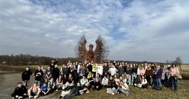 Bardzo liczna grupa młodzieży w szerokim planie na tle dużej figury orła.