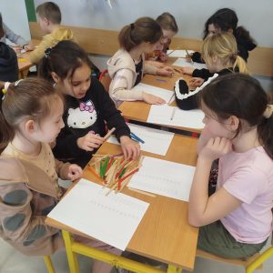 Uczniowie współpracując w parach, dzielą przy pomocy patyczków.