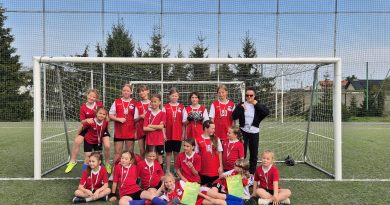 Zdjęcie grupowe dziewczyn z klas 3, 4, 5 po zakończonych rozgrywkach. Dziewczyny w czerwonych strojach sportowych