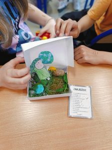 Uczniowie prezentują wykonane pudełko, w którym znajdują się znalezione skarby przyrody m.in. mniszek lekarski, skała, ziemia, liście.