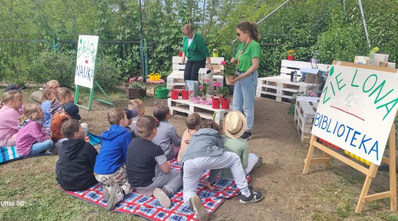 Stoisko Zielona Nauka, meble z palet , dzieci siedzą na kocach, pani pokazuje rośliny