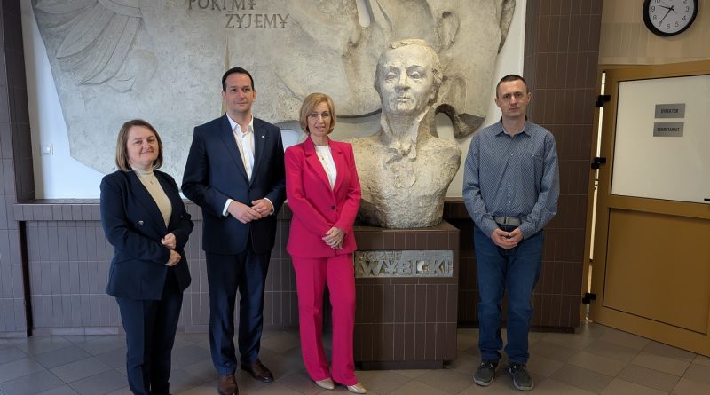 Wielkopolski Kurator Oświaty wraz z dyrekcją szkoły stoją na holu obok popiersia patrona szkoły, Józefa Wybickiego