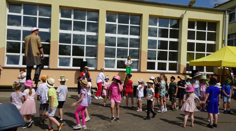 Parada uczniów z ozdobionymi głowami z Panem Kapelusznikiem na czele.