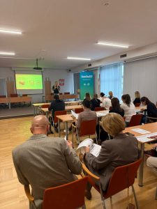 zdjęcie z tyłu sali, widać uczestników i prowadzącą