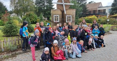 Zdjęcie grupowe klasy 1b i 1c z wychowawczyniami, a w tle wiatrak zbudowany ze słomy.