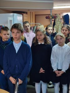 Na zdjęciu widoczna jest grupa ośmiorga uczniów – dwóch chłopców i sześciu dziewczynek – odświętnie ubranych.

Na pierwszym planie stoi chłopiec w białej koszuli i granatowym sweterku. Po prawej stronie kadru widoczna jest dziewczynka w granatowej sukience obok stoi dziewczynka w białej bluzeczce. W tle widać pozostałych uczniów, ustawionych w szeregu.