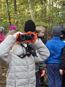 dziewczynka patrzy na drzewa przez lornetką