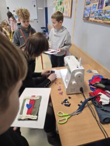 p. Ania szyje na maszynie, wokół stoją dzieci