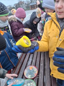 Uczniowie wyjmują z pojemników zamrożone lodowe rzeźby.