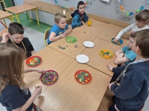 Uczniowie układają ekologiczne kompozycje na talerzykach.