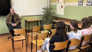 Uczennice siedzą na krzesłach na przeciwko prowadzącego