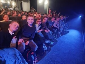 uczniowie w teatrze, na widowni oraz aktorami występującymi w spektaklu.