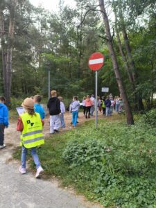 Uczniowie klas drugich idą na spacer i poszukują znaków drogowych.